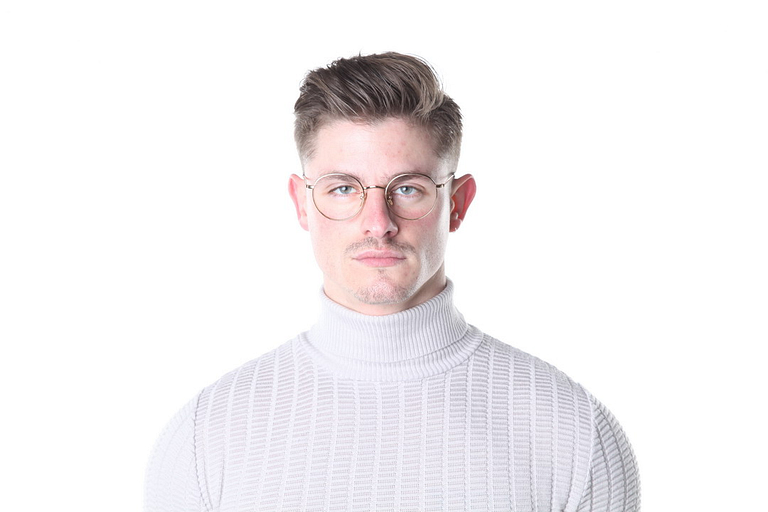 A man with glasses wearing a white turtleneck sweater against a white background.