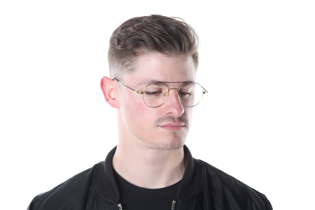 A young man with slicked hair and glasses looking away from the camera, against a white background.